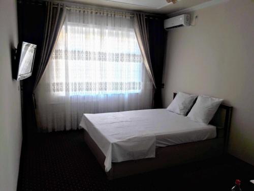 um pequeno quarto com uma cama e uma janela em Manzur em Fergana