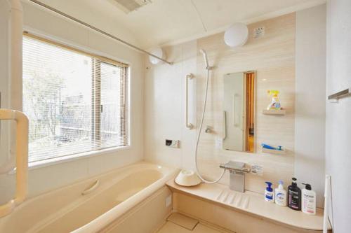 ein Bad mit einer Badewanne und einer Dusche mit einem Fenster in der Unterkunft Shinjuku Garden House in Tokio