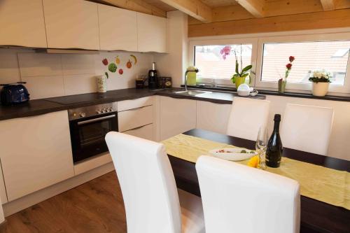 a kitchen with a table with white chairs and a counter top at Ferienwohnung Hanne in Untrasried