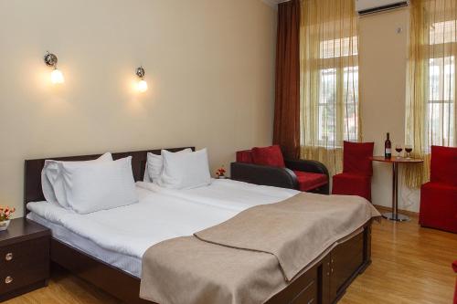 a hotel room with a large bed and red chairs at Hotel Nata in Tbilisi City