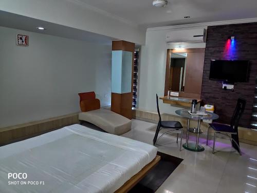 um quarto com uma cama, uma mesa e uma televisão em Hotel Easy Retreat em Vapi