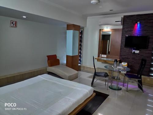 a bedroom with a bed and a table and a tv at Hotel Easy Retreat in Vapi
