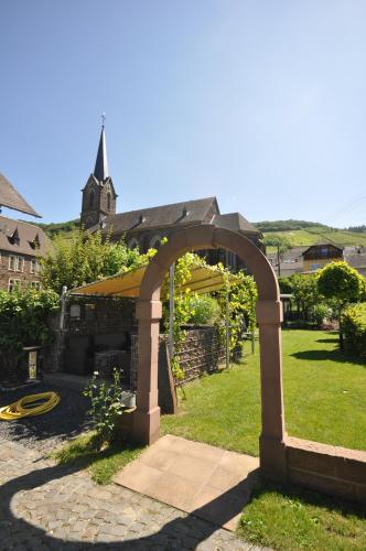 an archway in a yard with a church in the background at Gästezimmer im Weingut Amlinger&Sohn in Neef