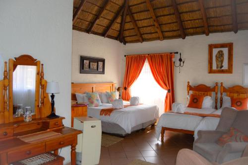 a bedroom with two beds and a couch and a window at Cheetau Lodge in Ebenhaezer