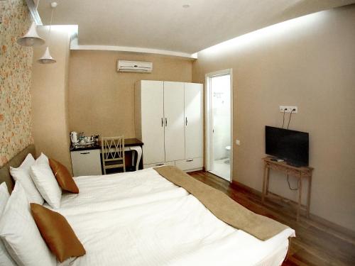 a bedroom with a large white bed and a television at Hotel Nata in Tbilisi City