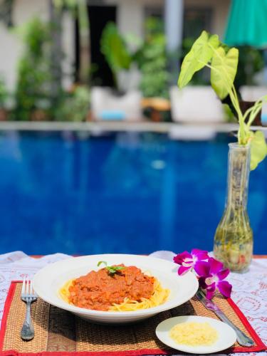 a plate of pasta on a table next to a pool at Moloppor Villa in Battambang