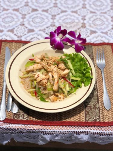 a plate of food with a salad and a purple flower at Moloppor Villa in Battambang
