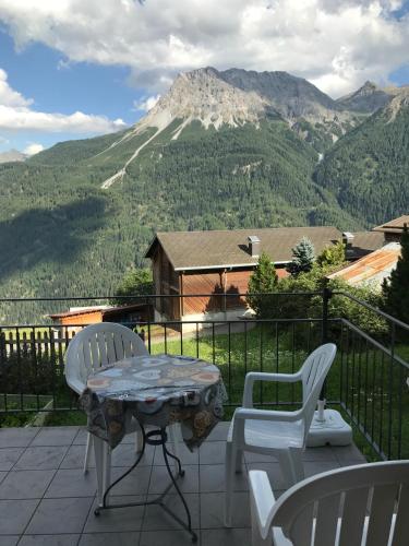 un patio con mesa, sillas y una montaña en Ferienwohnung in Tschlin mit Panoramablick, en Tschlin 
