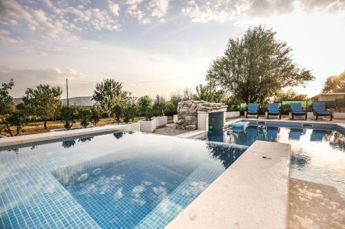 a swimming pool with blue chairs in a resort at Holiday Home Melone in Lećevica