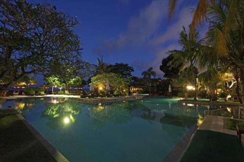 una grande piscina notturna con palme di Peninsula Beach Resort a Nusa Dua