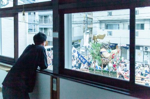 a person looking out of a window at a parade at Fukuoka Guesthouse HIVE in Fukuoka