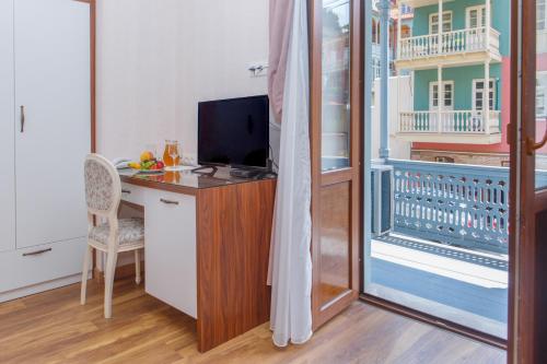 a room with a desk with a television and a balcony at Hotel Nata in Tbilisi City
