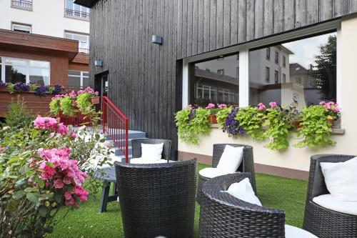 a patio with chairs and flowers in front of a building at Hotel de la Jamagne & Spa in Gérardmer