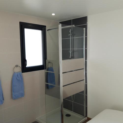 La salle de bains est pourvue d'une douche en verre et d'une fenêtre. dans l'établissement Ty Breizh, à Erdeven