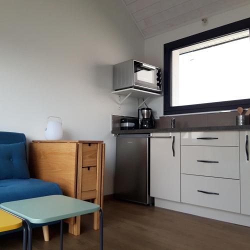 une petite cuisine avec un canapé bleu et une table dans l'établissement Ty Breizh, à Erdeven