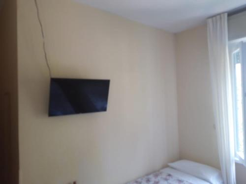 TV en la pared en una habitación con cama en B&B Hotel Delle Rose, en Torri del Benaco