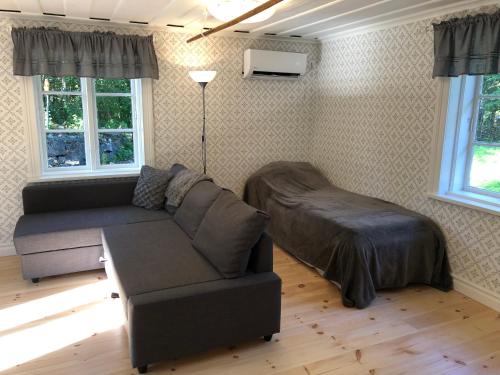 salon z kanapą i łóżkiem w obiekcie Nedanby | Cottage | Idyllic location | Porch | Grill w mieście Edsbro
