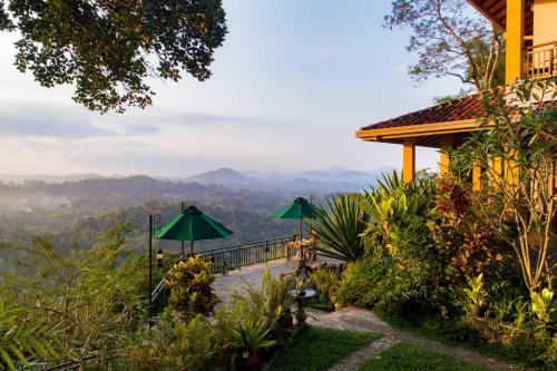 a house with green umbrellas and a view of the mountains at Villa Rosa in Kandy