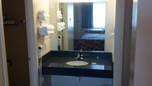 ein Bad mit einem Waschbecken, einem Spiegel und einem Bett in der Unterkunft Heritage House Motel in Prescott