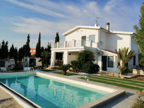 eine Villa mit einem Pool vor einem Haus in der Unterkunft Villa Eleonora in Marina di Ragusa