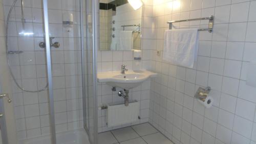 a white tiled bathroom with a sink and a shower at Ennstalerhof in Grossraming
