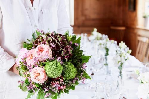 a person holding a bouquet of flowers on a table at Gasthof-Hotel Dannerwirt in Flintsbach