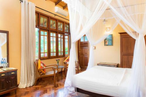 a bedroom with a bed with a white canopy at Villa Rosa in Kandy