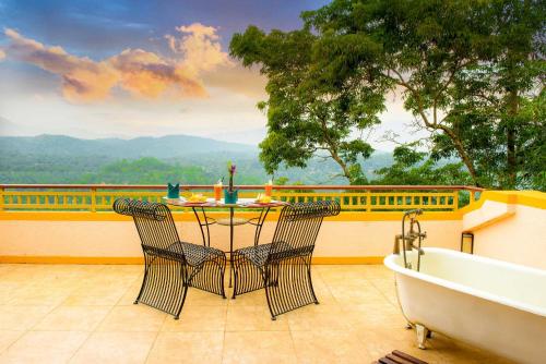 a table and chairs on a balcony with a bath tub at Villa Rosa in Kandy
