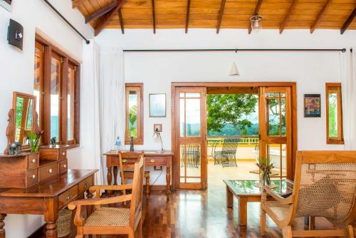 an open living room with a wooden desk and chairs at Villa Rosa in Kandy