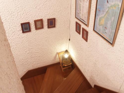 a stairwell with a light on a wall with pictures at Woody House Kazamidori in Myoko