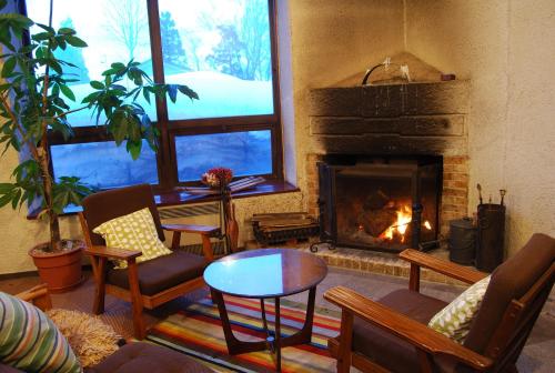 a living room with a fireplace with chairs and a table at Kogakuro in Myoko