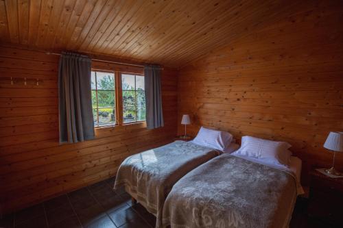 two beds in a log cabin with a window at Vogafjós Farm Resort in Myvatn