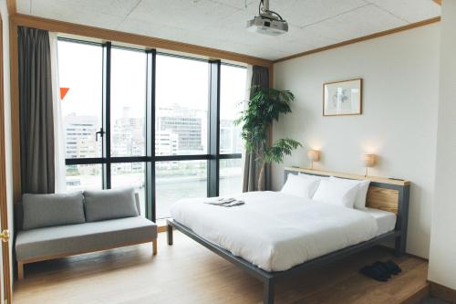 Schlafzimmer mit einem Bett, einem Stuhl und Fenstern in der Unterkunft Hotel Noum OSAKA in Osaka