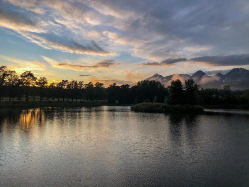 a sunset over a lake with trees and mountains at Guest House Privát Štrba in Štrba
