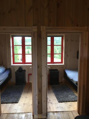 two beds in a wooden room with two windows at Nilsrud 30 Feriehus in Åmotsdal