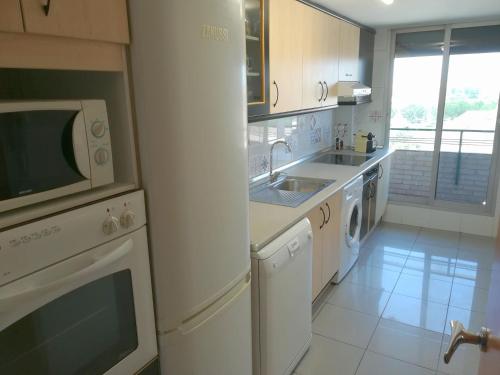 a white kitchen with a sink and a microwave at Ático BELLAVISTA con visita a bodega y cata de vinos 4 habitaciones dobles 2 baños completos in Tudela