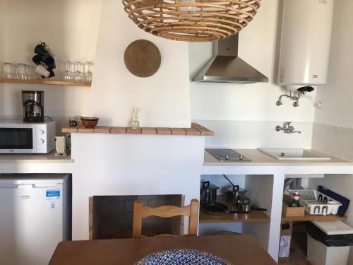 eine kleine Küche mit einem Tisch und einer Mikrowelle in der Unterkunft Casas de Mértola - N. Sª das Neves in Mértola