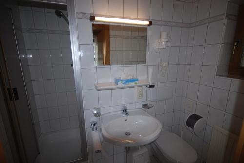 Baño blanco con lavabo y espejo en Pension Tirol, en Nauders