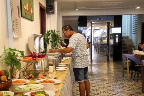 a man preparing food at a buffet in a restaurant at Grand Elevation Hotel in Phnom Penh