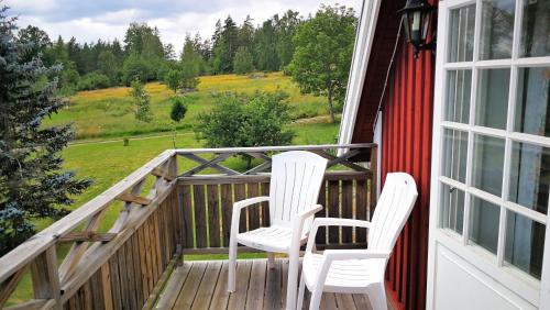 two white chairs sitting on a porch with a view at Vimmerby Lilla utsikten in Tuna