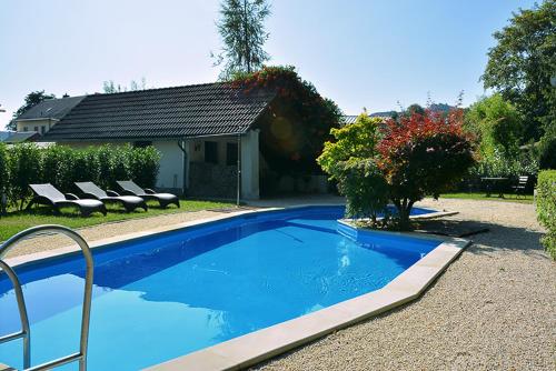 a blue swimming pool with lounge chairs next to a house at Ferienwohnung Sonne in Kurort Gohrisch