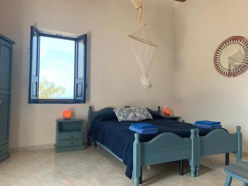 een slaapkamer met een blauw bed en een raam bij Luna Rossa in Ginostra