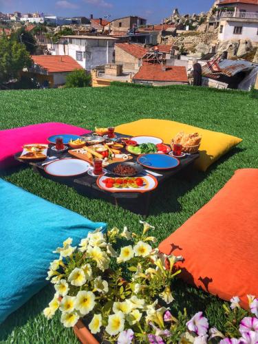Una mesa con platos de comida y flores sobre el césped. en Mahperi Cappadocia Cave, en Nevşehir
