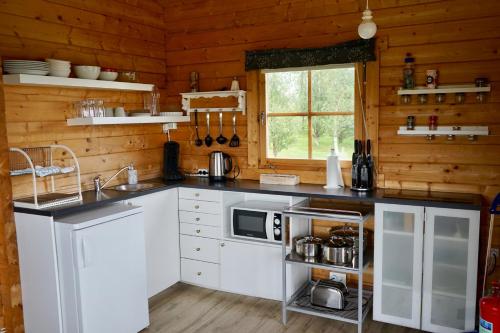 cocina con armarios blancos y encimera con microondas en Guesthouse Birkifell, en Nesjum