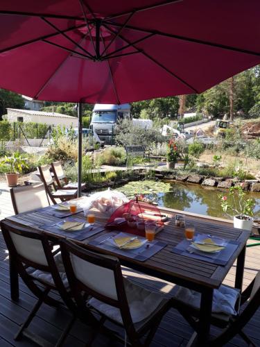 una mesa de madera con dos sillas y una sombrilla en Le Bois Bouquet Naos, en Saint-Cézaire-sur-Siagne