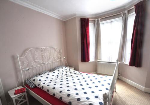 a bedroom with a white bed and two windows at East End London Garden Flat in London
