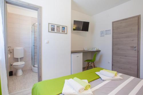 1 dormitorio con cama verde y baño en Room Elelina, en Cres