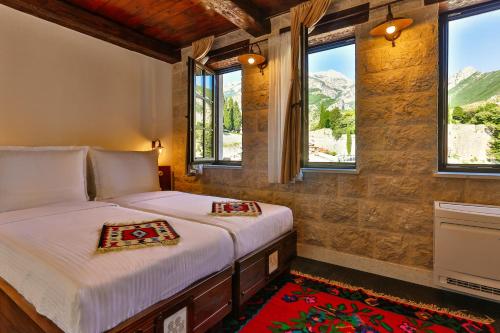 two beds in a room with windows and mountains at Stara Čaršija Hotel & SPA in Bar