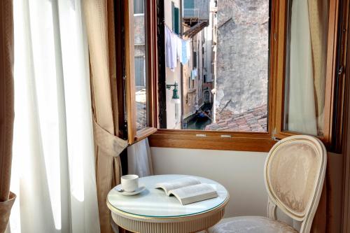 a small table with a book and a window at Nikki House in Venice