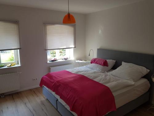 um quarto com uma cama com um cobertor vermelho e 2 janelas em Im Dobbenviertel mit Terrasse 3 Doppelzimmer 98qm em Oldenburg